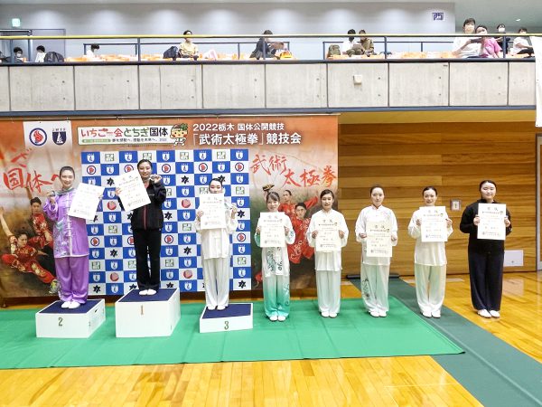 表彰台で笑顔を見せる成年女子総合太極拳（自選）の入賞者たち
