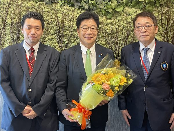 加藤勝信会長（中央）と。川﨑副会長兼専務理事（右）、長江事務局長（左）