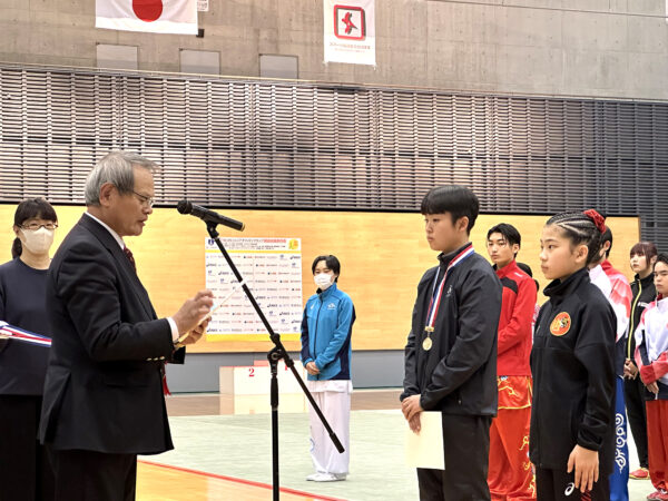 西村誠志常務理事より代表表彰を受ける川村心輝選手（岩手県連盟）と白川奏那選手（兵庫県連）